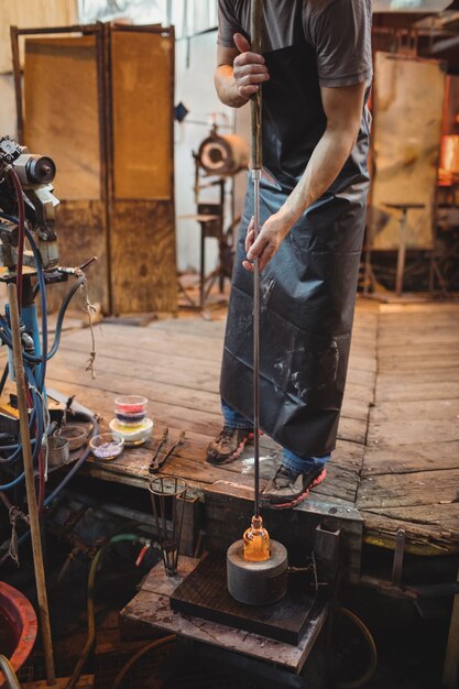 Glassblower using mold to shape a molten glass