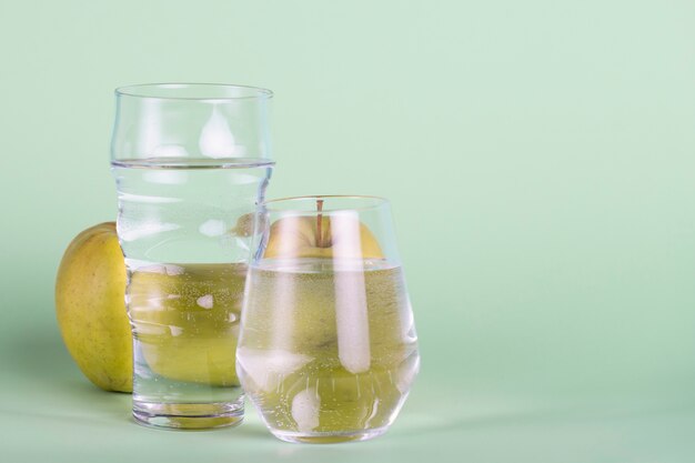 Glasses and apple on green background