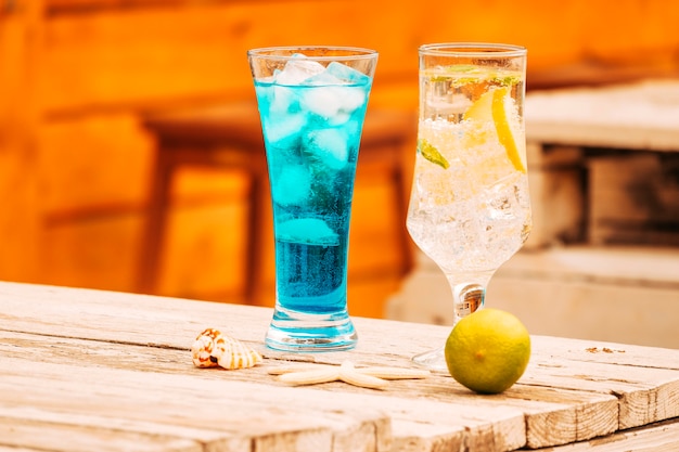 Foto gratuita bicchieri di bevande alla menta blu e calce con stelle marine al tavolo di legno