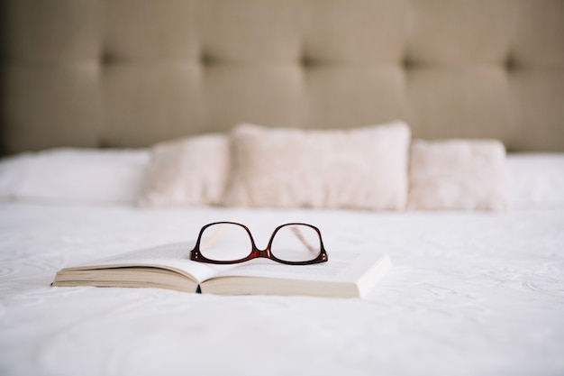 Glasses and book on bed