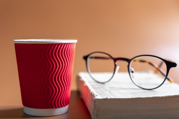 Foto gratuita occhiali un libro e un bicchiere di caffè di carta