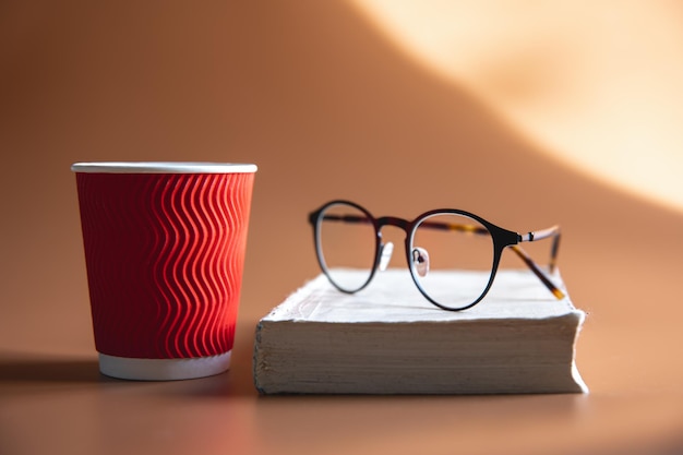 Free photo glasses a book and a paper glass of coffee