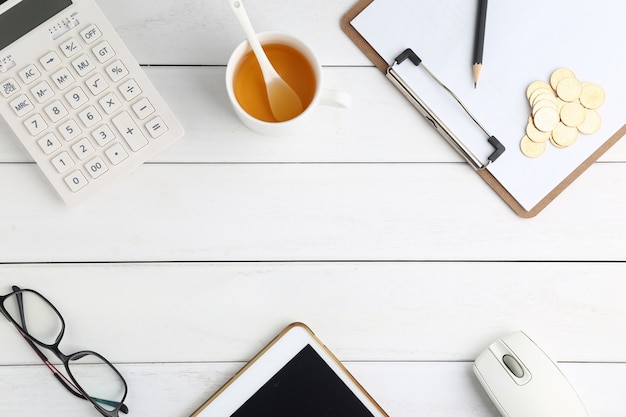 glasses, calculator,coins and tablet on white neat desk