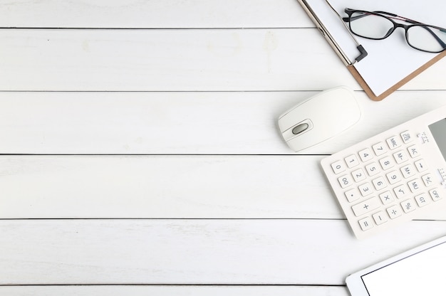 glasses, calculator and tablet on white neat desk