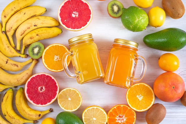 glasses of citrus juice and citrus fruits top view on wood table