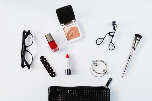 Glasses and cosmetics near stylish makeup bag