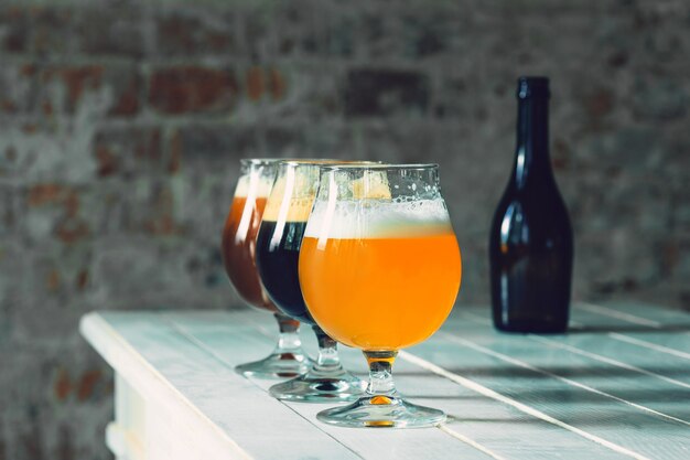 Glasses of different kinds of dark and light beer on wooden table in line. Cold delicious drinks are prepared for a big friend's party. Concept of drinks, fun, meeting, oktoberfest.