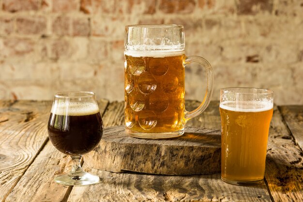 Glasses of different kinds of dark and light beer on wooden table in line. Cold delicious drinks prepared for a big friend's party. Concept of drinks, fun, meeting, oktoberfest.