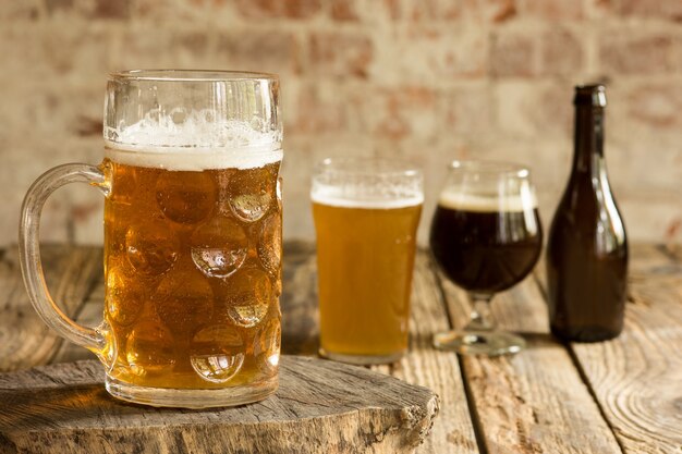 Glasses of different kinds of dark and light beer on wooden table in line.