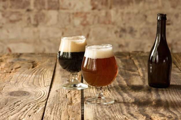 Glasses of different kinds of dark and light beer on wooden table in line