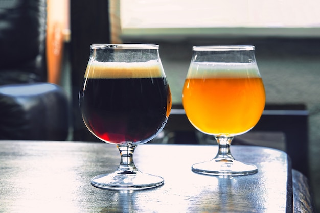 Glasses of different kinds of dark and light beer on wooden table in line