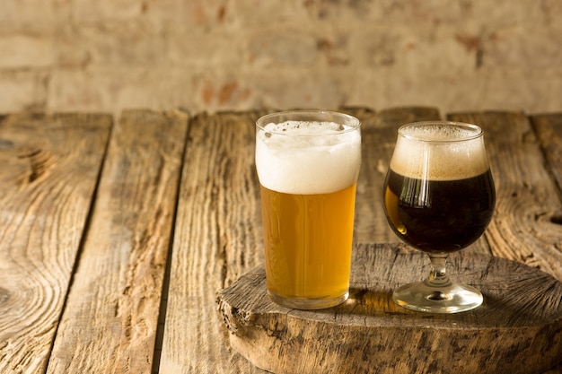 Glasses of different kinds of dark and light beer on wooden table