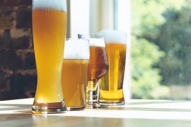 日光の下でさまざまな種類の軽いビールのグラス。