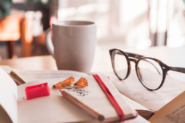 Glasses and mug near notebook and books