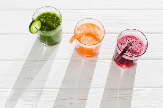 Glasses of multicolored smoothie on table