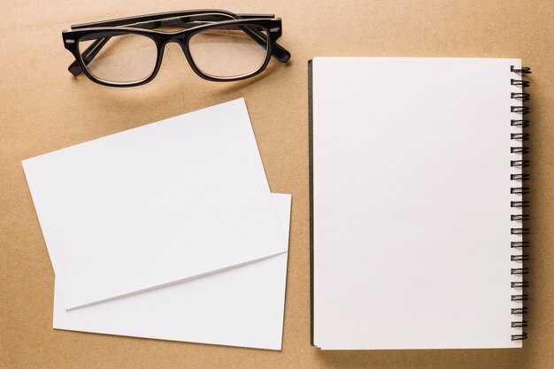 Glasses near notebook and paper sheets
