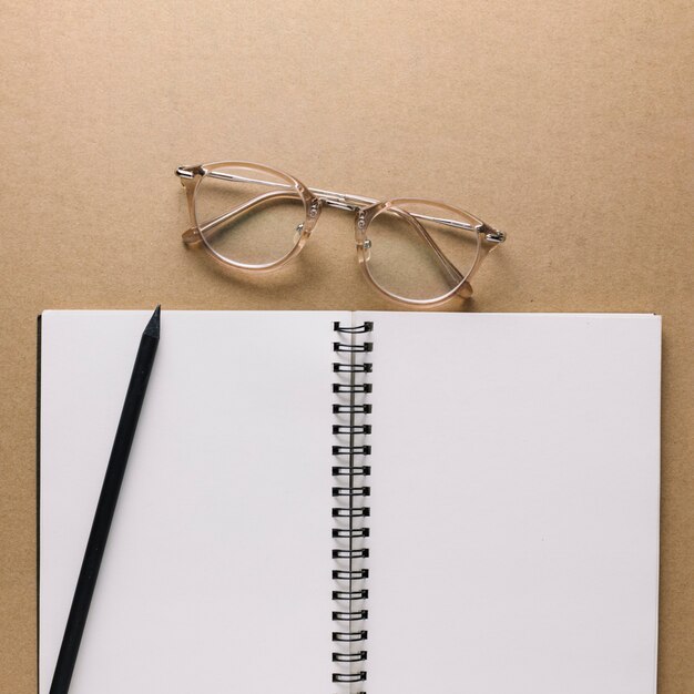 Glasses near notebook and pencil