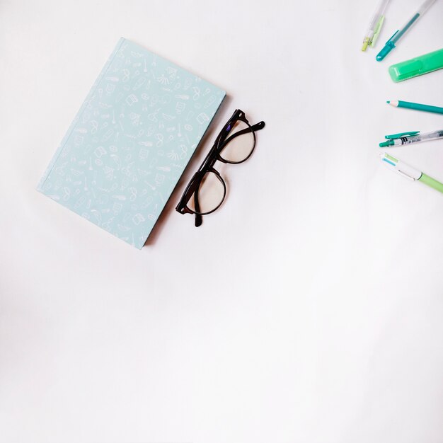 Glasses near notebook and pens