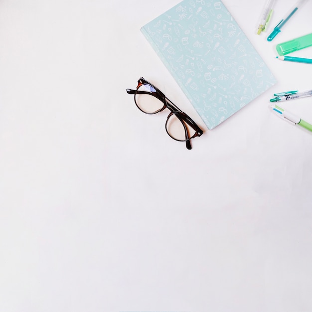 Glasses and notebook near writing supplies