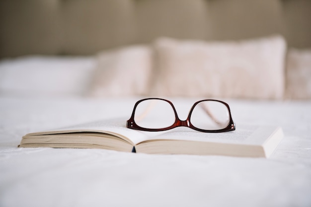 Glasses on opened book on bed