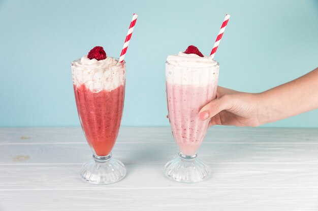 Glasses of raspberry milkshake with blue background