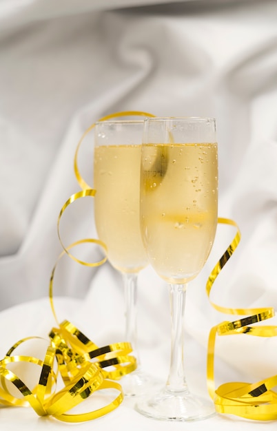 Glasses of refreshing champagne with golden streamers on white cloth