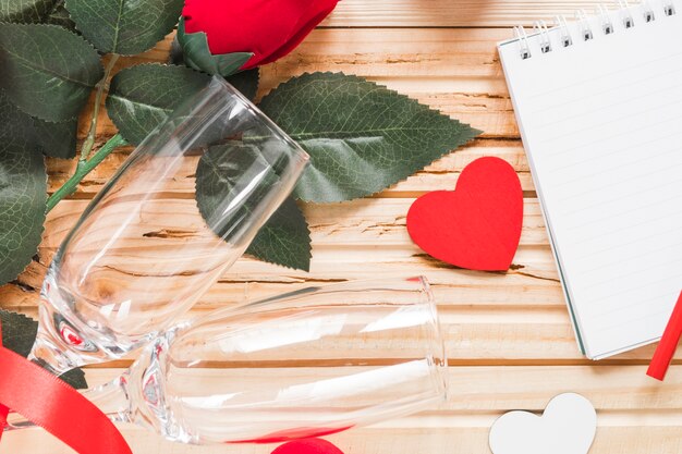 Glasses and rose near hearts and notebook