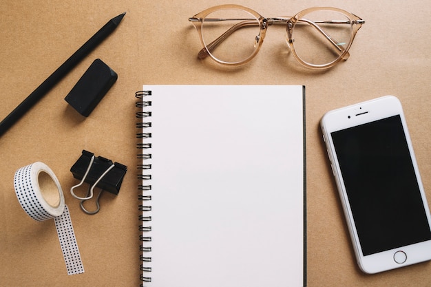 Glasses and smartphone near office supplies