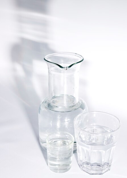 Стаканы воды и стакан с тенью на белом фоне