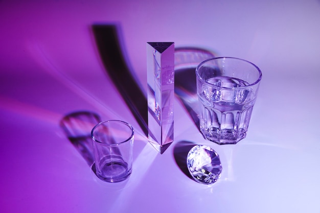 コップ一杯の水。プリズム;紫色の背景に影とダイヤモンド