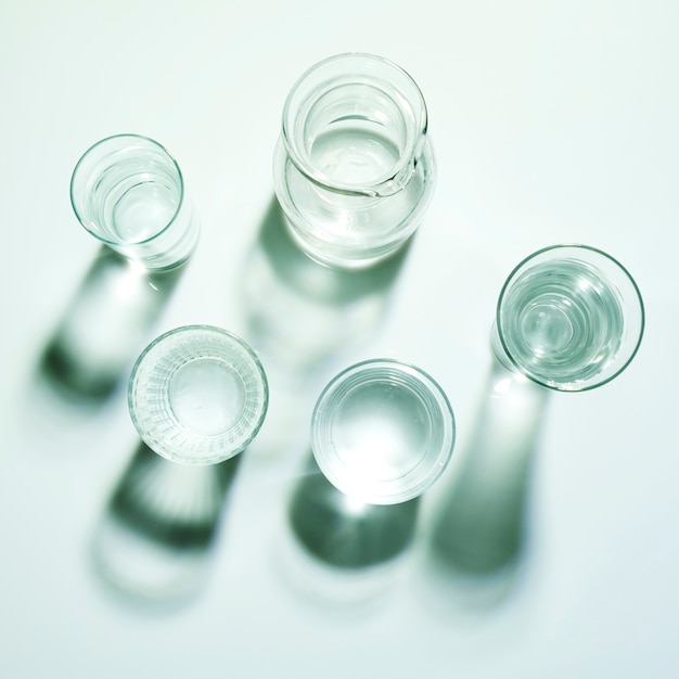 Glasses of water with jug on white backdrop