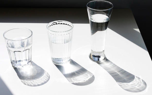 Glasses of water with shadow on white backdrop