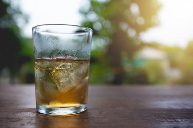 glasses of whiskey with ice cubes on wood.