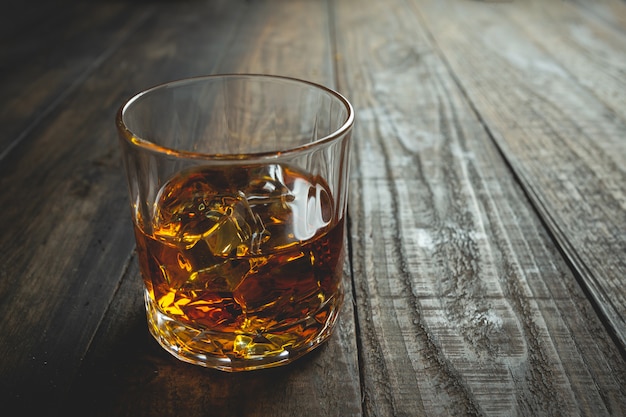 glasses of whiskey with ice cubes on wood.