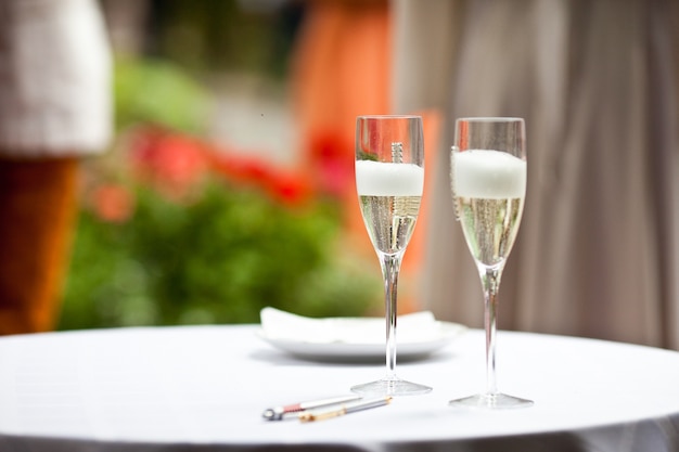 Glasses with champagne and foam stand on the white table