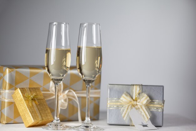 Glasses with champagne and gifts background