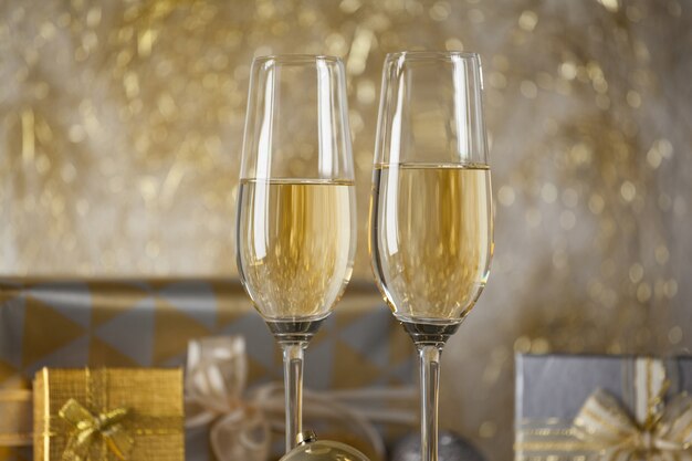 Glasses with champagne and gifts background