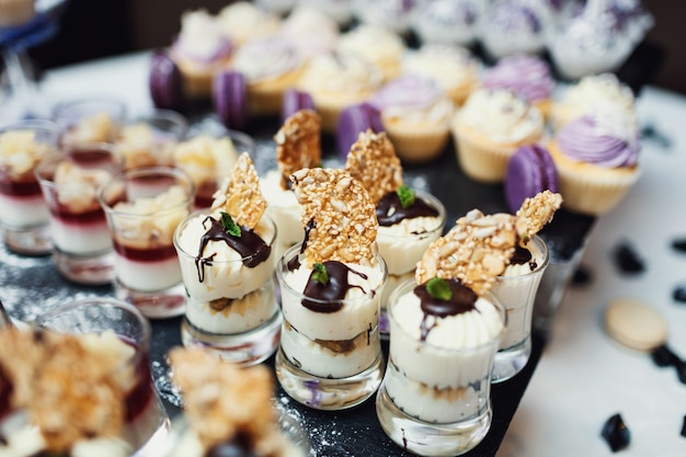 Glasses with cream and other sweets served on dinner plate