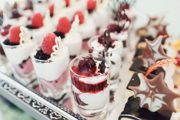 Glasses with desserts of berries served on large mirror
