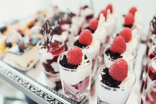 Glasses with desserts of berries served on large mirror