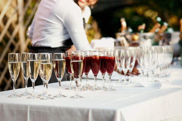 Glasses with red and white wine stand on the white dinner table