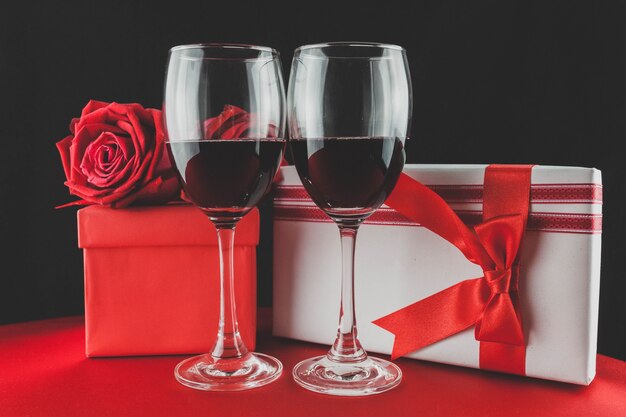 Glasses with red wine and two gifts