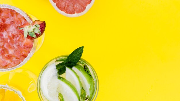 Glasses with strawberry and lime cocktails on yellow background