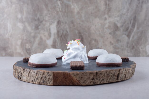 Glazed biscuit and chocolate wafer on board on marble table.