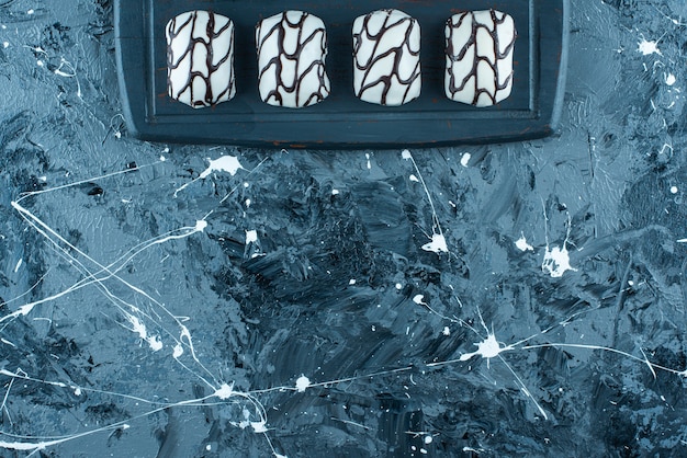 Free photo glazed candies on a tray, on the blue table.