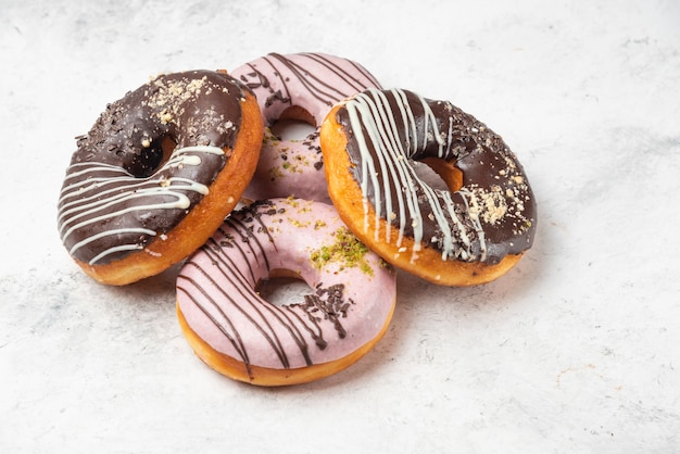 Free photo glazed chocolate and pink donuts on marble surface.