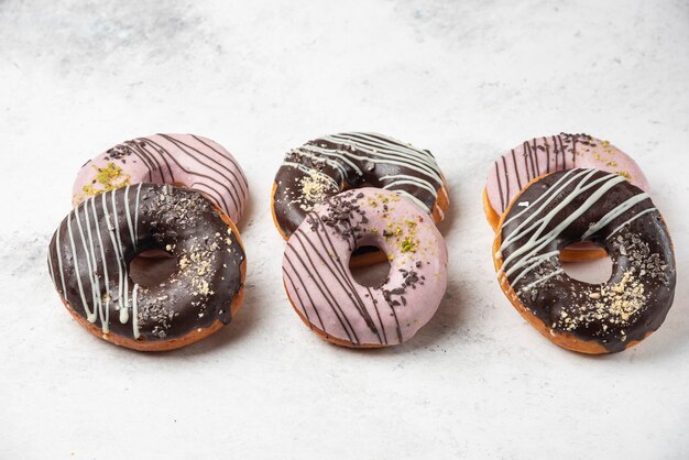 Glazed chocolate and pink donuts on white surface.