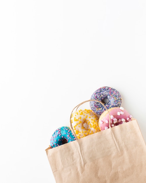 Free photo glazed colorful donuts in paper bag