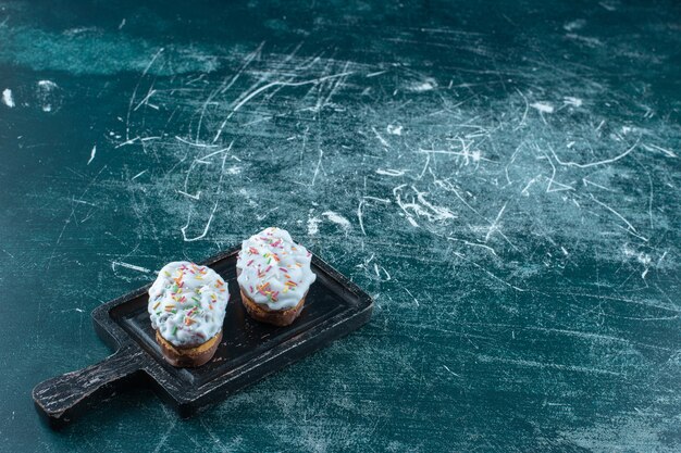 Glazed cookies on a board, on the blue surface