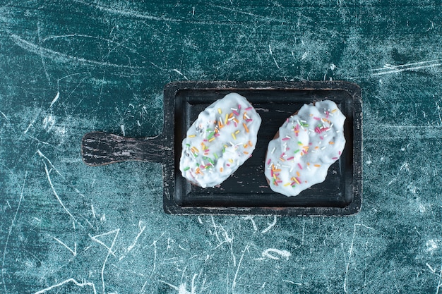 Glazed cookies on a board, on the blue table. 